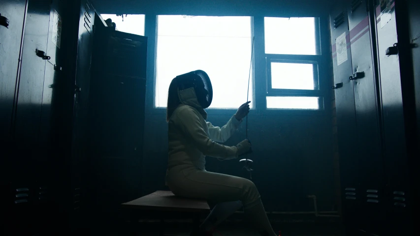 a woman sitting on a bench in front of a window, fencer, profile image, inside a dark room, gopro photo