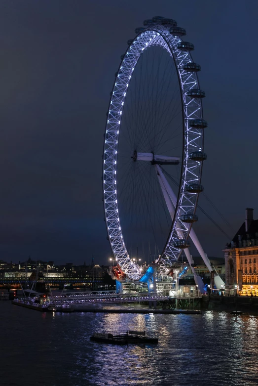 a large ferris wheel sitting next to a body of water, london at night, at night