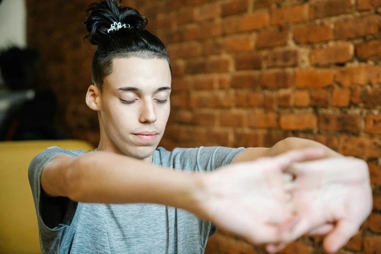 a woman stretching out her hands in front of a brick wall, trending on pexels, teen boy, acupuncture treatment, looking from shoulder, people with mohawks