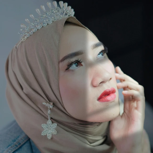 a woman in a hijab talking on a cell phone, a colorized photo, inspired by reyna rochin, trending on pexels, realism, silver prince crown, light make up, face accessories, asian face