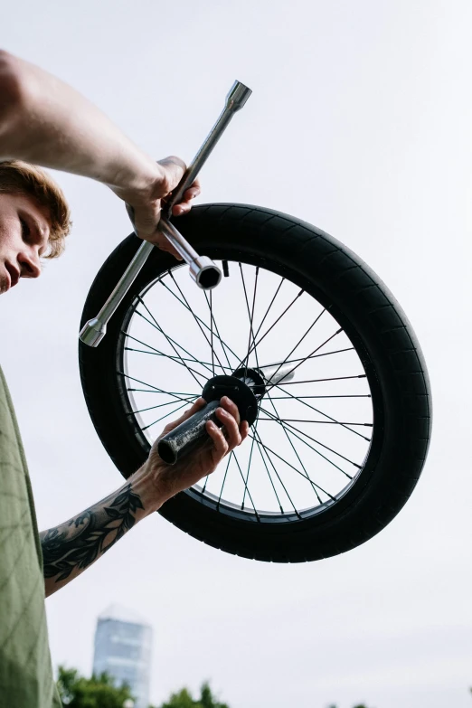 a man that is holding a bike wheel, on top of it