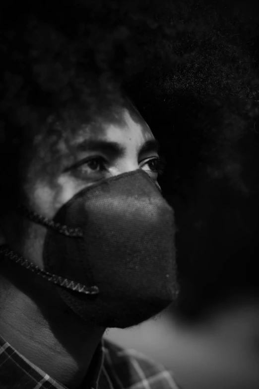 a black and white photo of a man with an afro, by Adam Marczyński, wearing facemask, plague mask, in focus face, concern