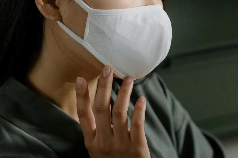 a woman wearing a face mask while talking on a cell phone, trending on pexels, hyperrealism, from the elbow, grey, wearing white cloths, round jawline