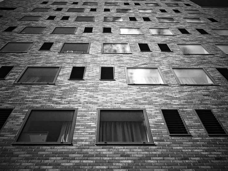 a black and white photo of a tall building, a black and white photo, inspired by Thomas Struth, unsplash, brutalism, house windows, bricks, berlin, taken on a 2000s camera