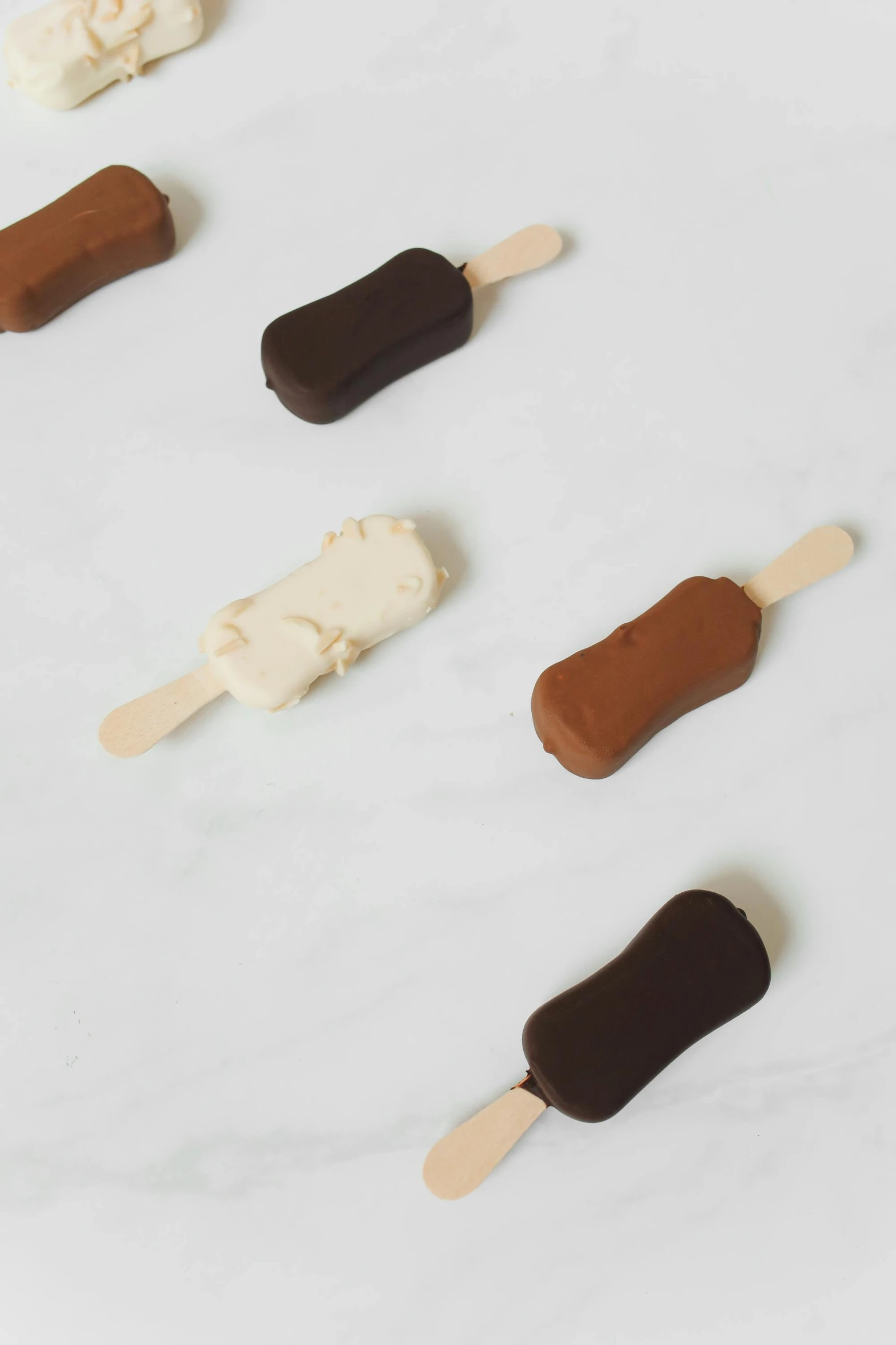 a group of ice cream pops sitting on top of a counter, dark sienna and white, matte finish, no cutoff, goddess shot