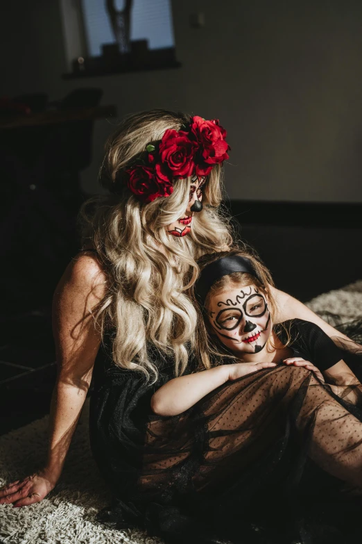 a woman sitting on top of a bed next to a little girl, a portrait, by Morgan Russell, pexels contest winner, skull face paint, black roses in hair, app, seasonal