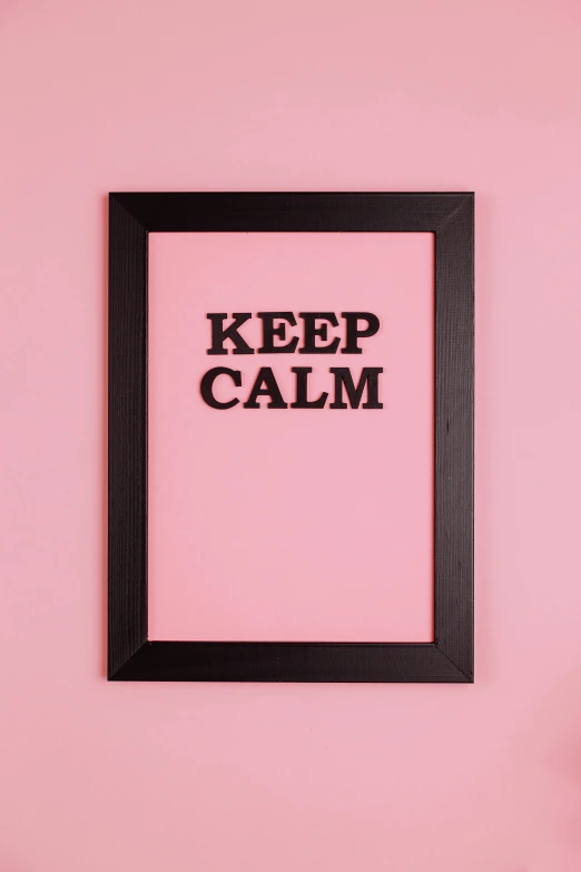 a pink wall with a black frame that says keep calm, poster art, pexels, demur, tilted frame, concept photo, a wooden