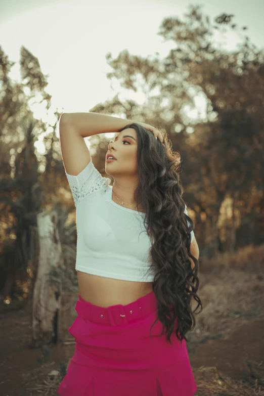 a woman in a white top and pink skirt, inspired by Elsa Bleda, pexels contest winner, long curly black hair, wearing a cropped tops, looking into the distance, alanis guillen