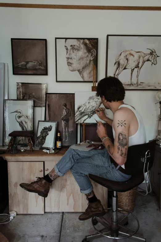a man sitting on a chair in front of a desk, a photorealistic painting, trending on pexels, pinterest tattoos, taxidermy, artist wearing overalls, moody neutral hipster tones