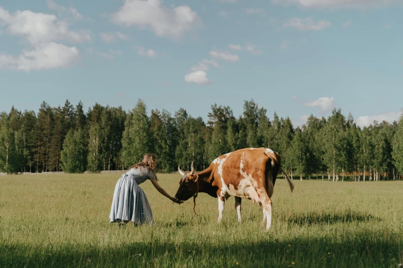 a woman standing next to a cow in a field, by Emma Andijewska, pexels contest winner, northern finland, al fresco, forest picnic, movie still of emma watson