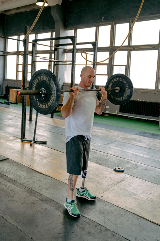 a man holding a barbell in a gym, by Adam Marczyński, extra limbs, bald, full body image, prosthetic leg