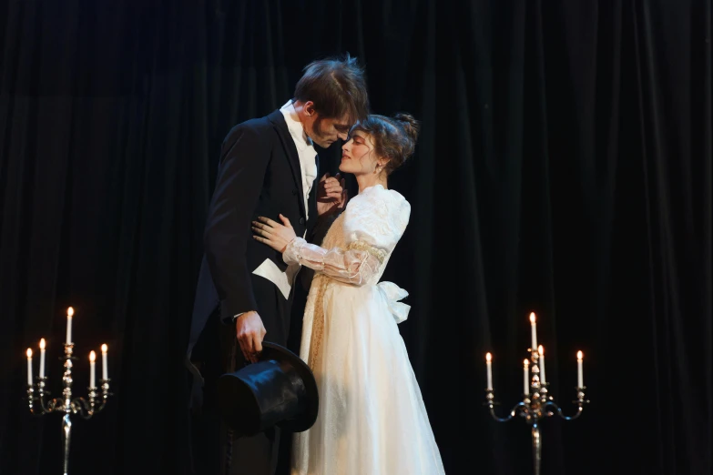 a couple of people standing next to each other on a stage, by Alice Mason, romanticism, wearing black old dress and hat, in a flowing white tailcoat, production photo, lachlan bailey