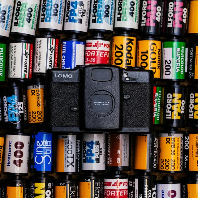 a camera sitting on top of a pile of film, front facing the camera, 2 2 0 film, back to the camera, dramatic product shot