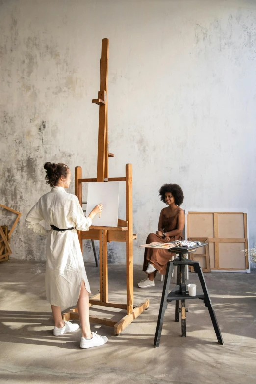 a woman standing in front of a painting easel, by Caro Niederer, pexels contest winner, academic art, two models in the frame, sao paulo, tranding on art station, raw sienna