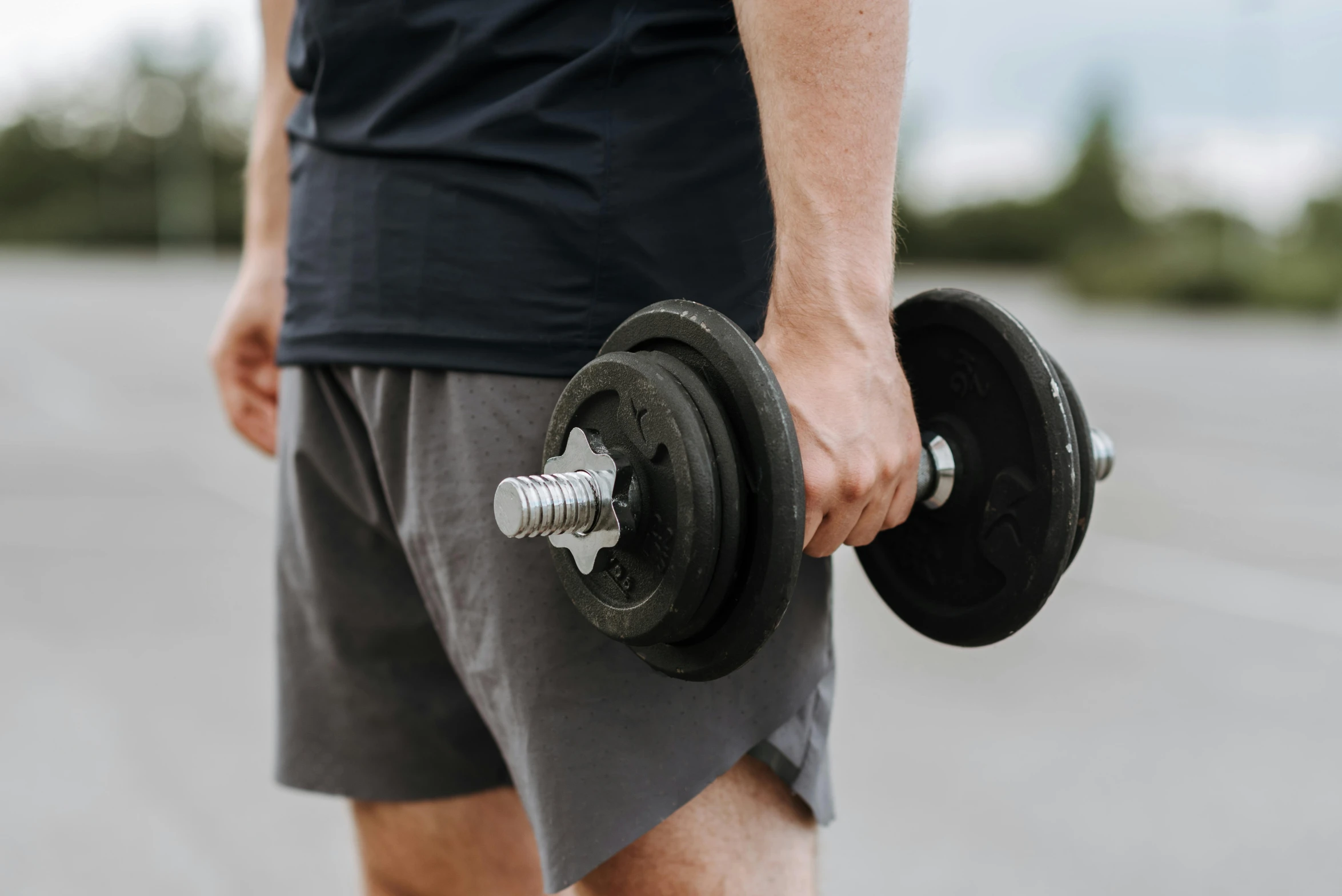 a close up of a person holding a pair of dumbbells, by Carey Morris, pexels contest winner, lachlan bailey, exterior shot, arms to side, where a large