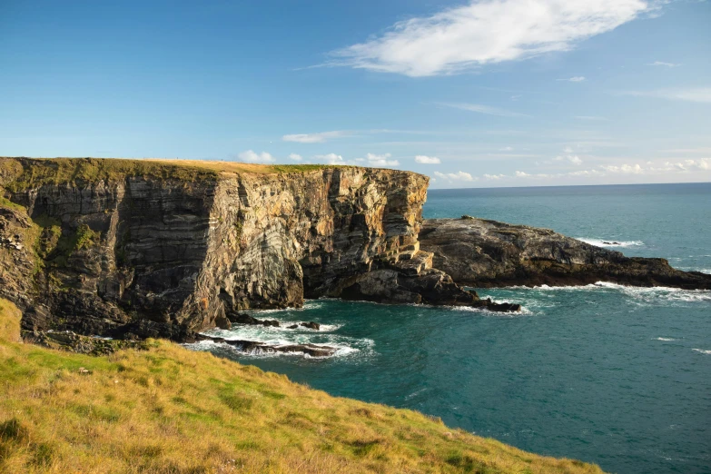 a man standing on top of a cliff next to the ocean, by Bedwyr Williams, les nabis, rock arches, distant photo