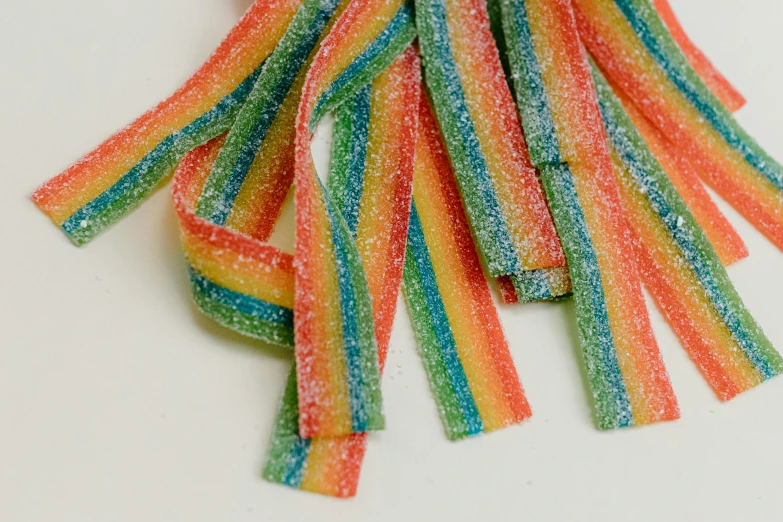 a pile of gummy candy sitting on top of a table, rainbow neon strips, thick bow, product shot, detail shot