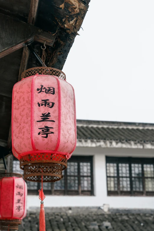 a couple of red lanterns hanging from the side of a building, a silk screen, slight overcast weather, square, style of guo hua, high quality photo