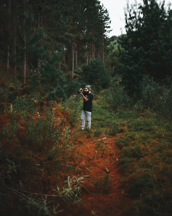 a man standing in the middle of a forest, a polaroid photo, unsplash contest winner, carrying a rifle, lush surroundings, distant photo, a high angle shot