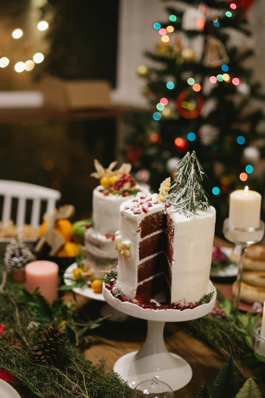 a cake sitting on top of a table next to a christmas tree, by Julia Pishtar, pexels contest winner, renaissance, red brown and white color scheme, profile image, multiple stories, white table