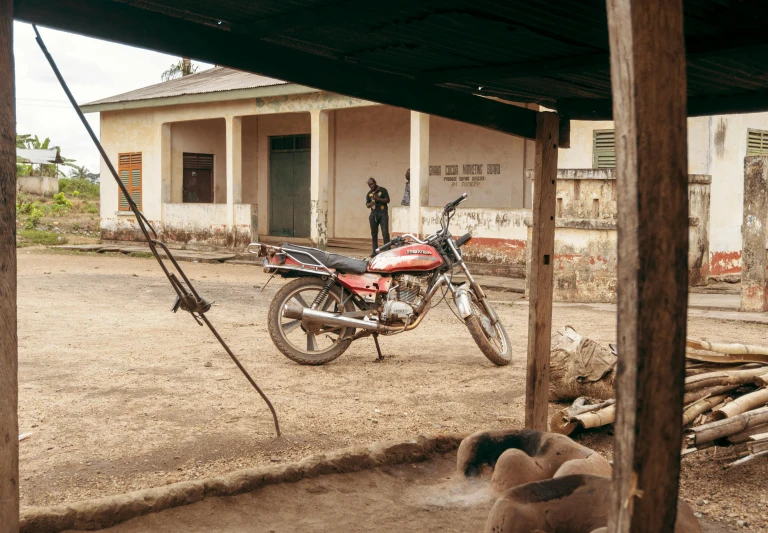 a motorcycle parked in front of a building, by Daniel Lieske, on a village, laura zalenga, rural, in the yard