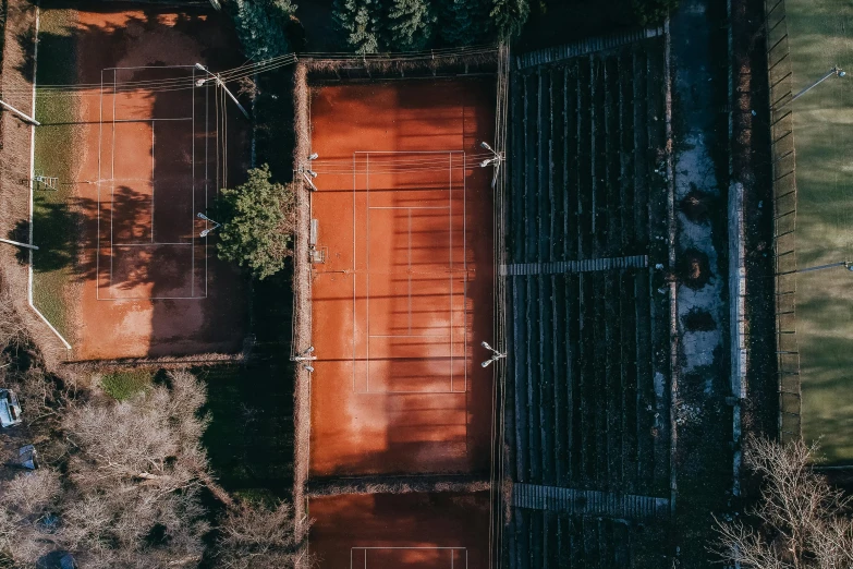 an aerial view of a tennis court surrounded by trees, by Jan Tengnagel, unsplash contest winner, modernism, rusted panels, 15081959 21121991 01012000 4k, evening lighting, terracotta