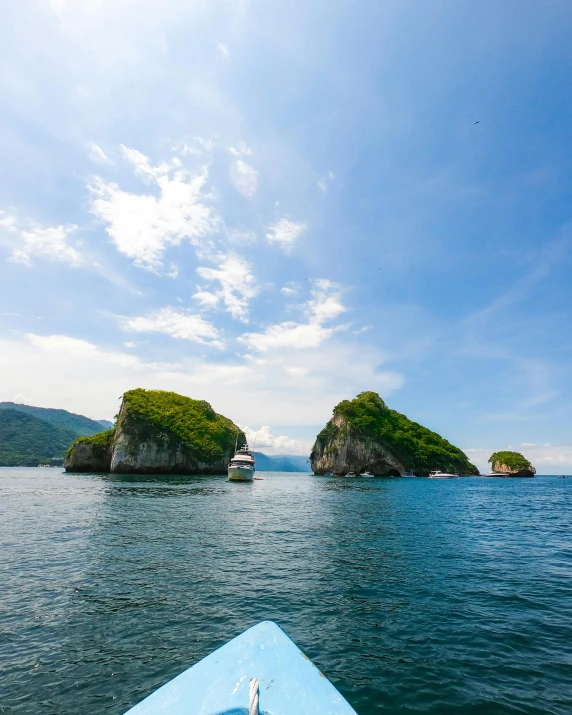 a boat in the middle of a body of water, two medium sized islands, thumbnail, rock arcs, lush surroundings