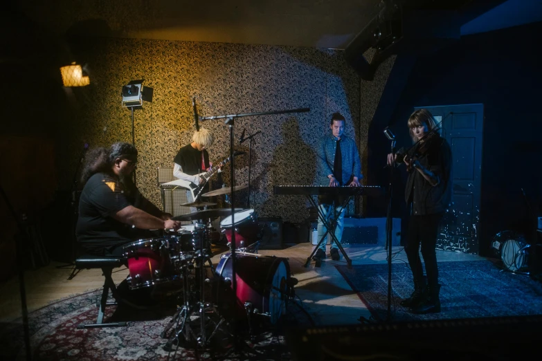 a group of people playing instruments in a room, an album cover, unsplash, private press, low lights, ignant, tv show still, b - roll