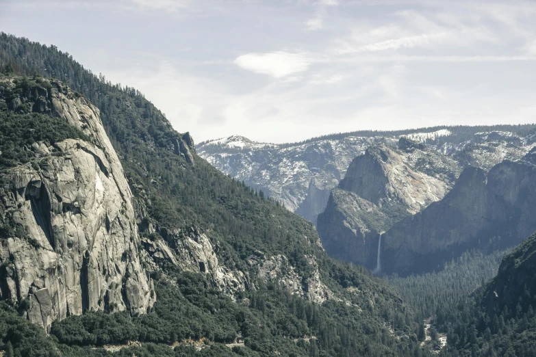 a view of a valley with mountains in the background, pexels contest winner, yosemite, grey, trees and cliffs, panoramic