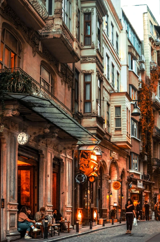 a group of people walking down a street next to tall buildings, by Cafer Bater, pexels contest winner, art nouveau, humid evening, istanbul, storefront, baroque detailed