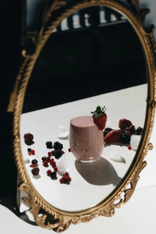 a mirror sitting on top of a table next to a cup, by Emma Andijewska, pexels contest winner, renaissance, squashed berries, vanilla smoothie explosion, velvet, product shot