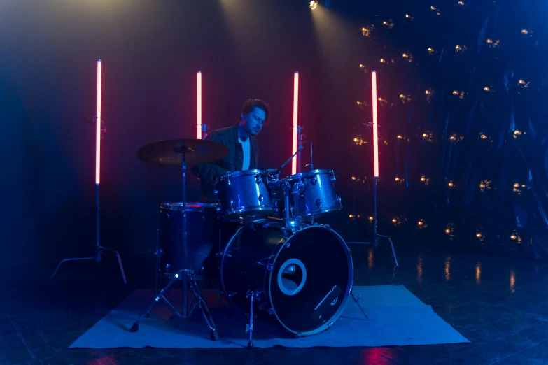 a man that is sitting in front of a drum, cinematics lighting, blue lights, shot on alexa, colour corrected