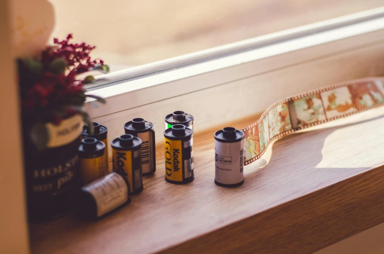 a couple of rolls of film sitting on top of a window sill, a picture, unsplash, visual art, vintage photo, medium format