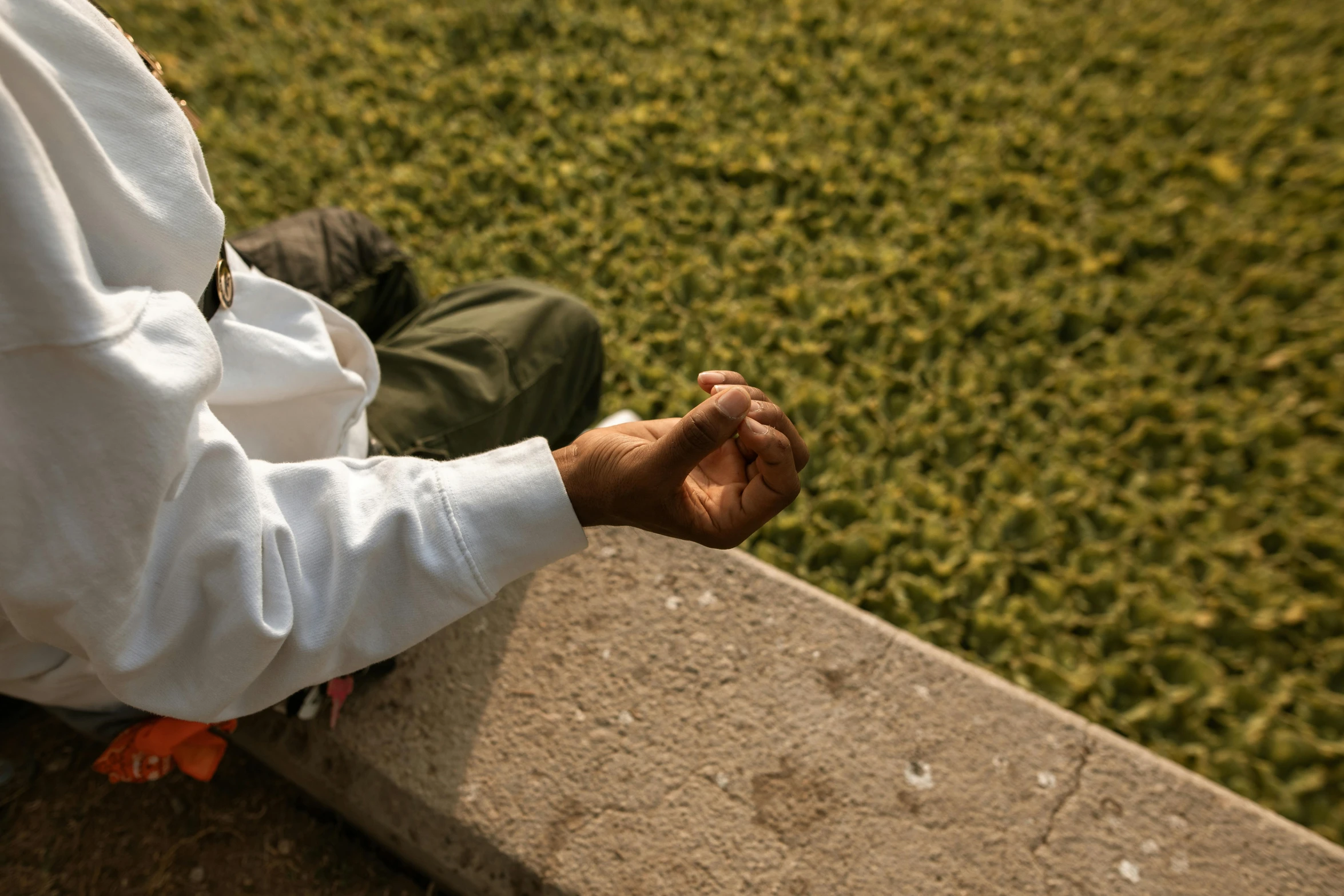 a man sitting on top of a cement bench, an album cover, inspired by Gordon Parks, unsplash, hand gesture, people resting on the grass, dressed in an old white coat, ayahuasca ceremony