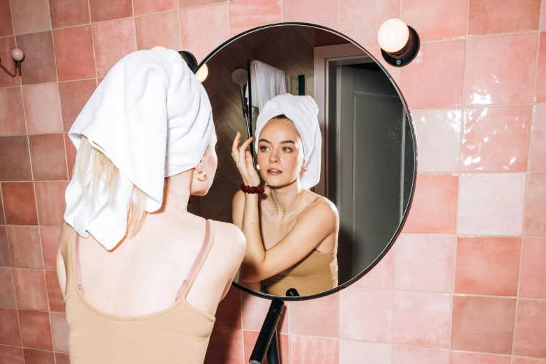 a woman that is standing in front of a mirror, wearing a towel, eva elfie, showing forehead, round mirror on the wall