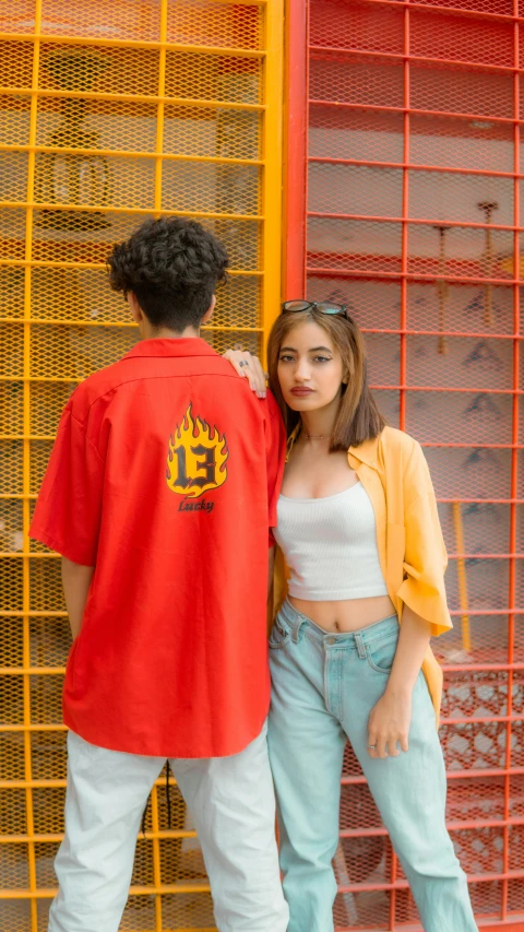 a man and a woman standing next to each other, an album cover, inspired by Cafer Bater, pexels contest winner, wearing red and yellow clothes, lalisa manobal, outlive streetwear collection, shot with canon eoa 6 d mark ii