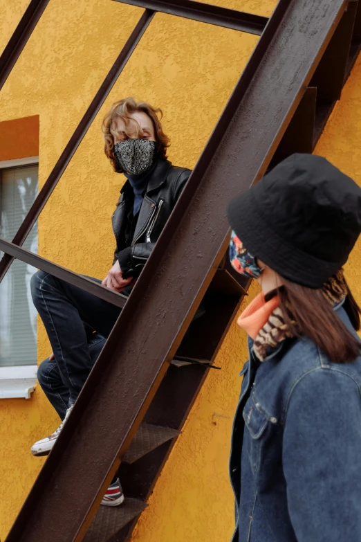 a woman standing in front of a window talking on a cell phone, an album cover, by Attila Meszlenyi, trending on reddit, graffiti, black bandana mask, standing on a ladder, two models in the frame, wearing jeans and a black hoodie