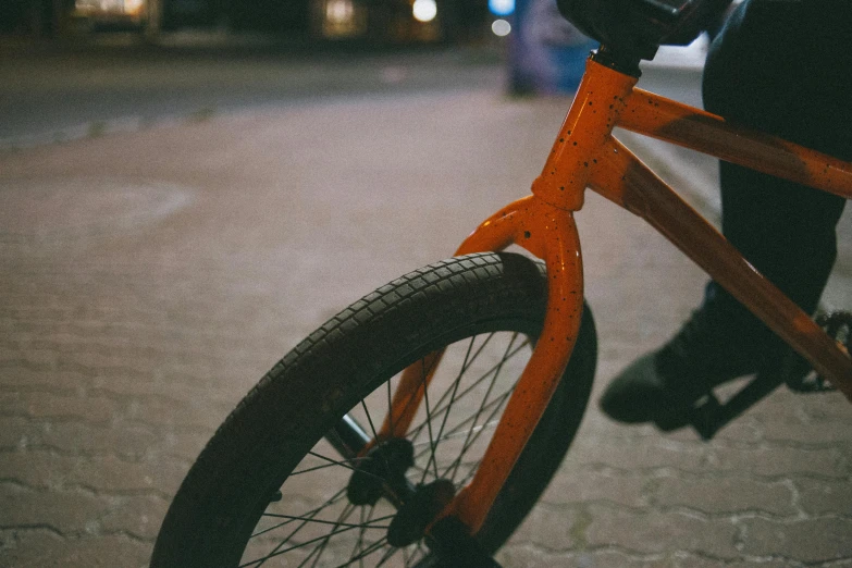 a person riding a bike on a city street, pexels contest winner, realism, black and orange, close-up shot, childish, nighttime