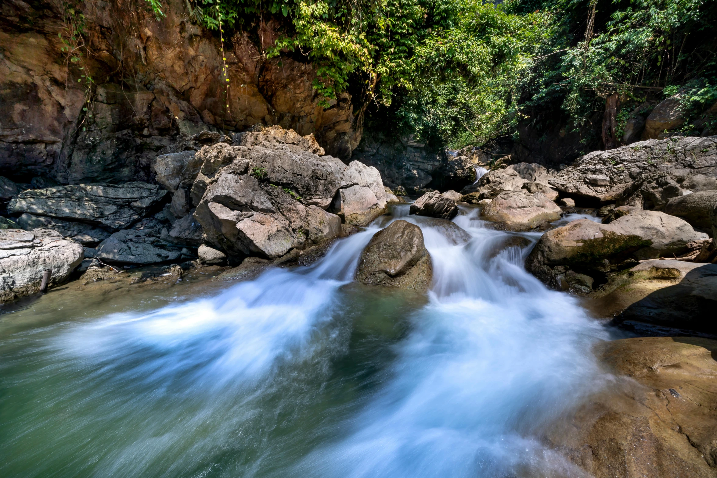 a river running through a lush green forest, by Alexander Brook, pexels contest winner, sumatraism, white water rapids, thumbnail, wet rocks, sri lanka