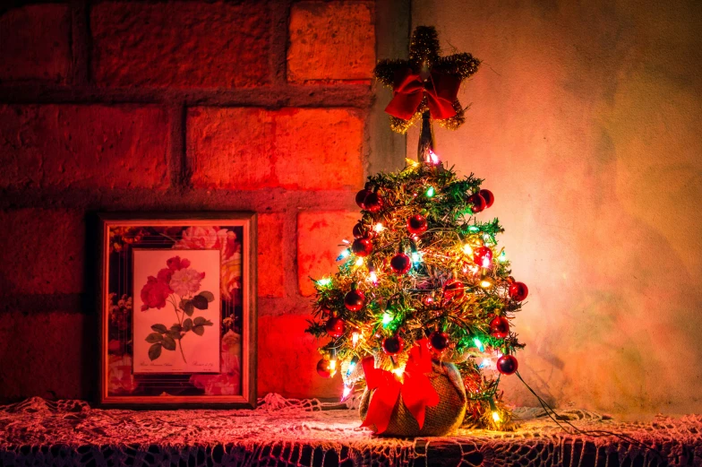 a small christmas tree sitting on top of a table, pexels, red and yellow light, ivy's, fully decorated, night mood