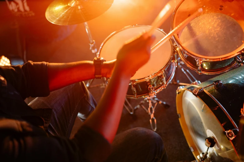 a man sitting in front of a drum set, by Matt Cavotta, shutterstock, warm orange lighting, closeup - view, band playing instruments, 15081959 21121991 01012000 4k