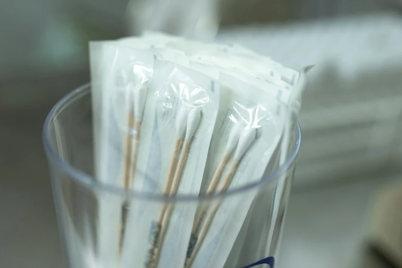 a glass filled with toothbrushes sitting on top of a counter, unsplash, process art, urine collection bag, high samples, smoking, in a research facility