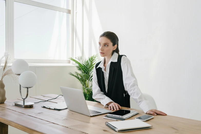 a woman sitting at a desk in front of a laptop computer, by Carey Morris, trending on pexels, wearing black vest and skirt, wearing a white button up shirt, lachlan bailey, very minimal