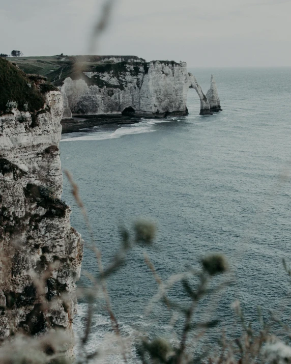 a couple of people standing on top of a cliff next to the ocean, pexels contest winner, romanticism, white stone arches, northern france, low quality photo, farming