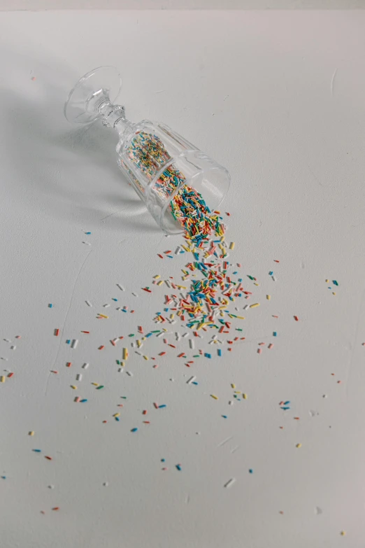 a bottle filled with sprinkles sitting on top of a table, pexels, visual art, broken parts, ilustration, made of plastic, minimal composition