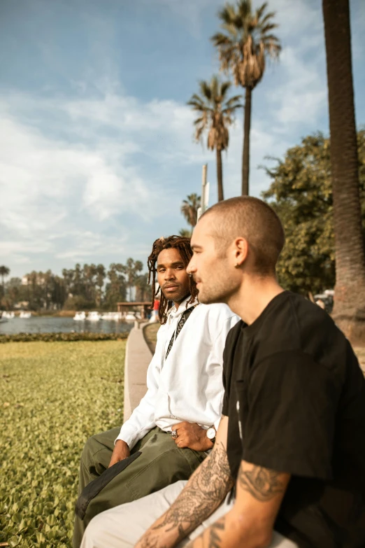 a couple of men sitting next to each other on a bench, a portrait, trending on unsplash, palm trees in the background, teddy fresh, profile image, los angelos