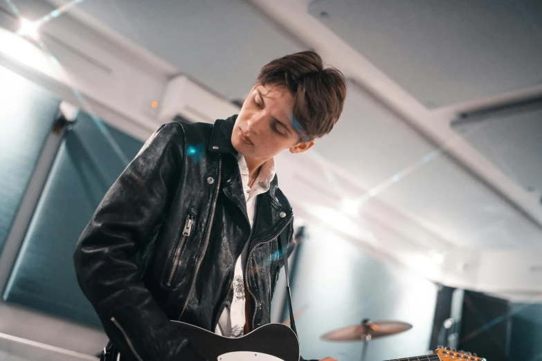 a man in a leather jacket playing a guitar, by Emma Andijewska, pexels contest winner, bauhaus, declan mckenna, live performance, julian ope, 15081959 21121991 01012000 4k