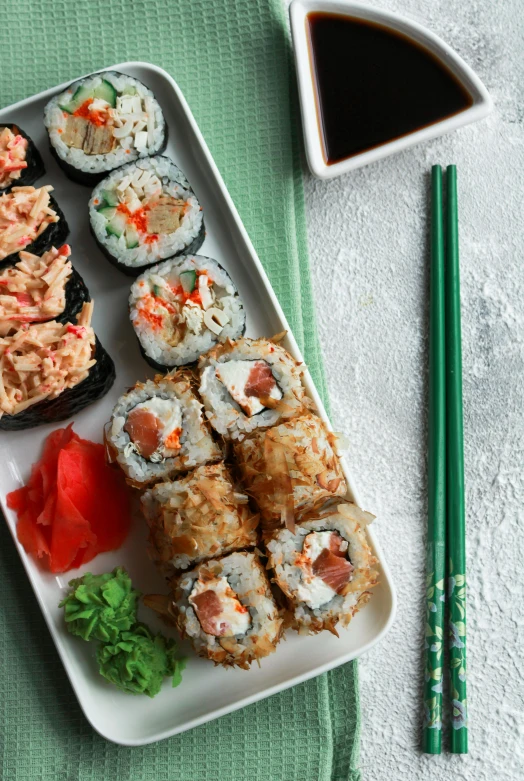 a white plate topped with sushi next to chopsticks, 6 pack, coral, heavenly, skyline showing