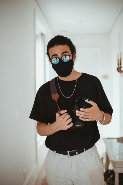 a man wearing a face mask and holding a camera, asher duran, teddy fresh, mid shot photo, middle eastern