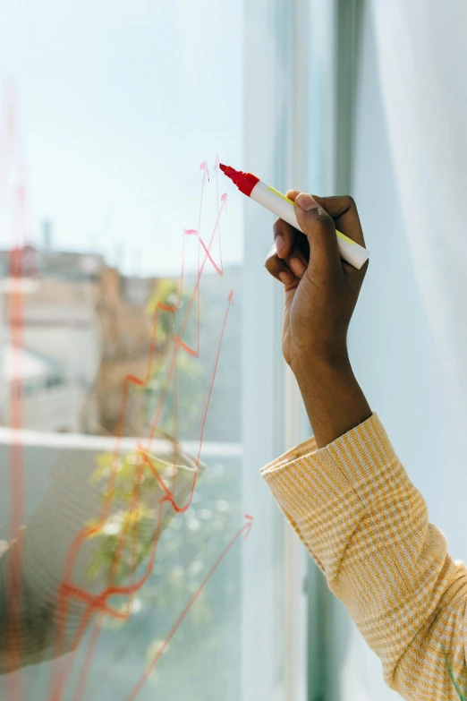 a person writing on a window with a marker, bright colors with red hues, data visualization, promo image, transparent